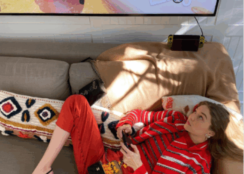 gigi hadid on a couch in a red outfit playing a game