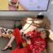 gigi hadid on a couch in a red outfit playing a game