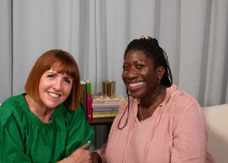 two women smiling in a podcast studio
