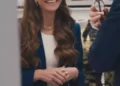 Long-haired brunette woman smiles while talking with another person in an elegant indoor setting