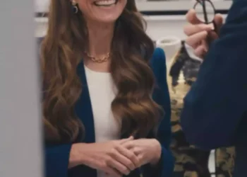 Long-haired brunette woman smiles while talking with another person in an elegant indoor setting