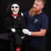 Man holding a Billy puppet from the film Saw III