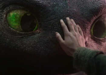 How To Train Your Dragon's Mason Thames places his hand on dragon Toothless' pebbled black face. .