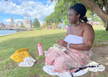 Akelo Agingu, of Cranston, sits under a tree in Providence’s 195 District Park, near the Point Street Bridge Sunday afternoon, Aug. 24, while crews prepare the bridge for filming J.J. Abrams’ “Ghostwriter” that night.