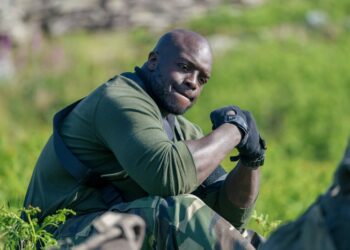 Adebayo Akinfenwa sat down wearing a harness and gloves at Hang Tough location.