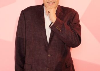 Mark Labbett from Celebs Go Dating, smiling and touching his chin.