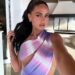 Woman in purple tie-dye dress taking selfie.