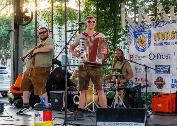 A man playing the accordion and another joining him with the trumpet at a German themed venue.