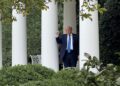 President Trump pumps his fist as he tests out the new outdoor speaker system in the Rose Garden