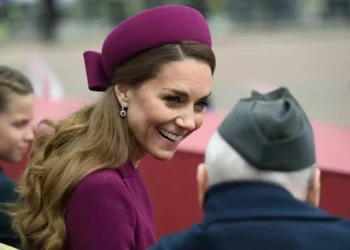 A smiling woman in a purple hat talks with an older man wearing a gray cap.