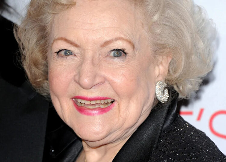 Betty White smiles on the red carpet, wearing a black outfit with sparkling details and silver earrings