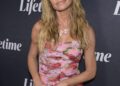 Denise Richards poses on the red carpet at a Lifetime event in a strapless pink floral dress, wearing her hair in loose waves and holding a pink clutch.