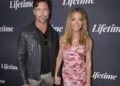 Aaron Phypers and Denise Richards hold hands while posing on the red carpet at a Lifetime event, with Phypers in a black leather jacket and Richards in a strapless pink floral dress.