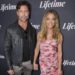 Aaron Phypers and Denise Richards hold hands while posing on the red carpet at a Lifetime event, with Phypers in a black leather jacket and Richards in a strapless pink floral dress.