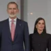 Felipe with a red tie and Letizia dressed in black serious looking to the side