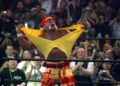 A man in a bandana, heavily tanned and with a mustache, rips his shirt inside a wrestling ring.