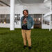 Ryan Patrick Hooper poses on the grass set inside the Boyer Campbell Building in Detroit for the Petrichor botanical art installation on May 30, 2024. (Photo credit: Tayler Simpson, WDET)