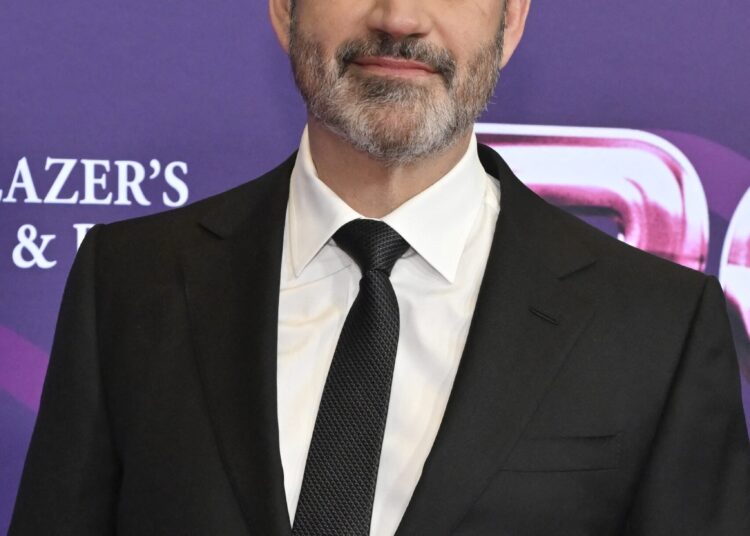 Jimmy Kimmel wearing a dark suit and tie at a red carpet event