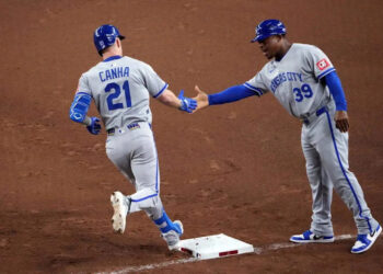 Kansas City Royals outfielder Mark Canha (21) slaps hands with Kansas City Royals first base coach Damon Hollins (39) after hitting a solo home run against the Arizona Diamondbacks during the fifth inning at Chase Field on July 4, 2025.