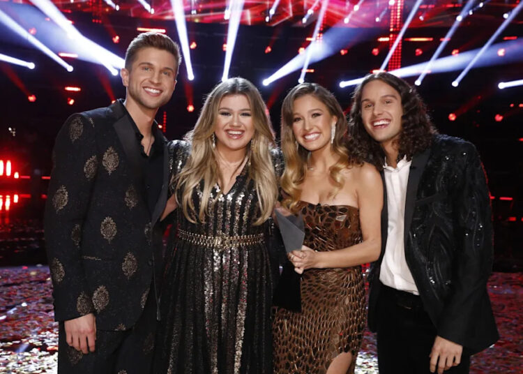 THE VOICE, Kelly Clarkson (2nd from left), with winners Girl Named Tom (Caleb Liechty, Bekah Liechty, Joshua Liechty), 'Live Finale', (Season 21, ep. 2126, aired Dec. 14, 2021). photo: Trae Patton / ©NBC / courtesy Everett Collection