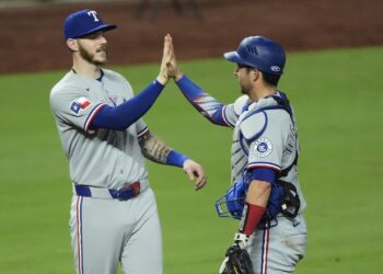 Texas Rangers' Jonah Heim, left, and Kyle Higashioka celebrate after their baseball game against the Kansas City Royals, Wednesday, Aug. 20, 2025, in Kansas City, Mo. (AP Photo/Charlie Riedel)