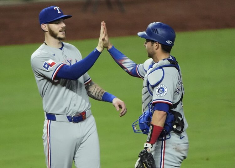 Texas Rangers' Jonah Heim, left, and Kyle Higashioka celebrate after their baseball game against the Kansas City Royals, Wednesday, Aug. 20, 2025, in Kansas City, Mo. (AP Photo/Charlie Riedel)