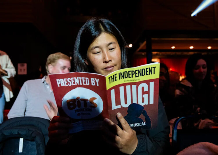 Bryn Levitan reads the show program before watching “Luigi: The Musical,” written by several Bay Area comedians, about three high-profile inmates being held in a Brooklyn prison. - (Camille Cohen/For The Washington Post)