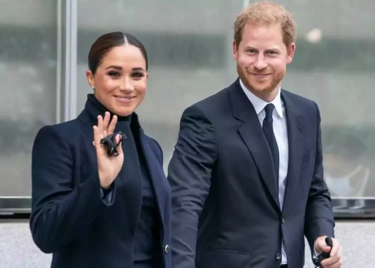 Meghan Markle and Prince Harry dressed formally, both smiling and walking together, she is waving.
