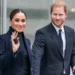 Meghan Markle and Prince Harry dressed formally, both smiling and walking together, she is waving.