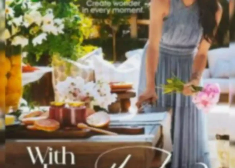 Meghan Markle in a light blue dress stands next to a table decorated with flowers and food in a garden, with the text