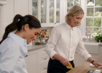 Meghan Markle and Clare Smyth working in a white kitchen and smiling