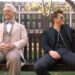 Michael Sheen and David Tennant smile on a park bench on Good Omens