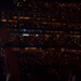 Crowd at a concert with lit-up phones emanating red light.