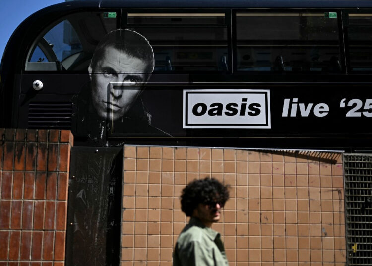 A person walks past an Oasis themed bus in Manchester, northern England on July 11, 2025, ahead of the British rock band's highly-anticipated second leg of their reunion tour. The return of the prodigal Oasis brothers to Manchester Friday, on the second leg of their highly-anticipated reunion tour, has rekindled memories of the city's time as a cultural epicenter.