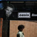 A person walks past an Oasis themed bus in Manchester, northern England on July 11, 2025, ahead of the British rock band's highly-anticipated second leg of their reunion tour. The return of the prodigal Oasis brothers to Manchester Friday, on the second leg of their highly-anticipated reunion tour, has rekindled memories of the city's time as a cultural epicenter.