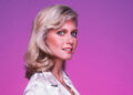 A close-up of Olivia Newton-John looking perplexed in white.