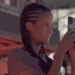 Young person with braids recording a video with their phone at an indoor event