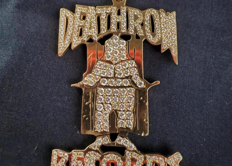 A diamond-encrusted Death Row Records pendant on a dark background, shared by