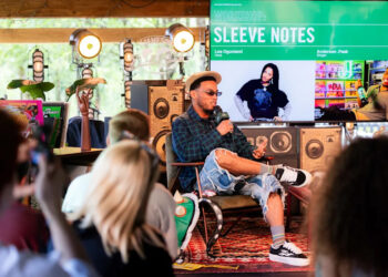 Anderson .Paak is seated on stage, speaking into a microphone at a workshop titled