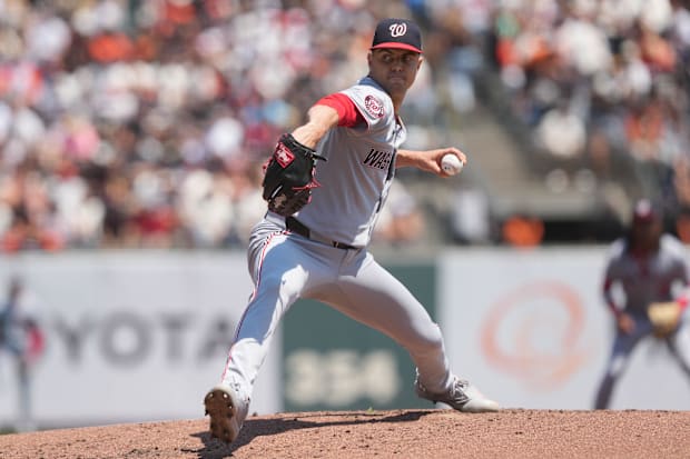 Gore in a solid grey jersey throwing a ball against the giants out of a black glove wearing a black and red ha