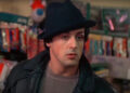 Sylvester Stallone's Rocky inside pet store wearing his black hat and black leather jacket.