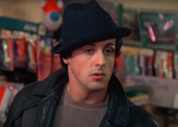 Sylvester Stallone's Rocky inside pet store wearing his black hat and black leather jacket.