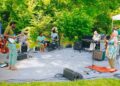 Musicians perform on a blanket in a park