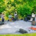 Musicians perform on a blanket in a park