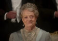 Dame Maggie Smith sits dressed in her finest smiling at a ball in Downton Abbey: The Movie.