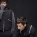 Tyler Joseph and Josh Dun pose against a black backdrop dressed in dark outfits