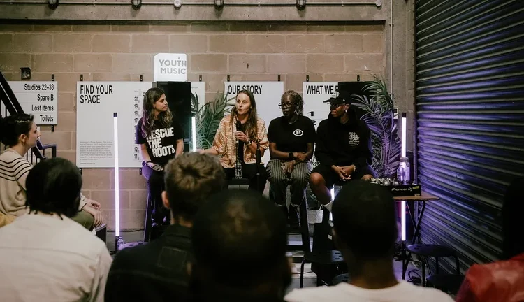 a panel of people sit on chairs in front of an audience