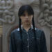Wednesday in front of Medusa-shaped fireplace outdoors in Wednesday Season 2.