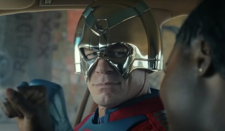 John Cena as Peacemaker wearing his vigilante costume and smiling sadly on Peacemaker