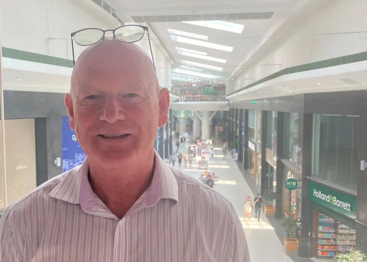 Photograph of Mike Matthews from the Grand Arcade shopping centre. he is pictured with the shopping mall behind him.